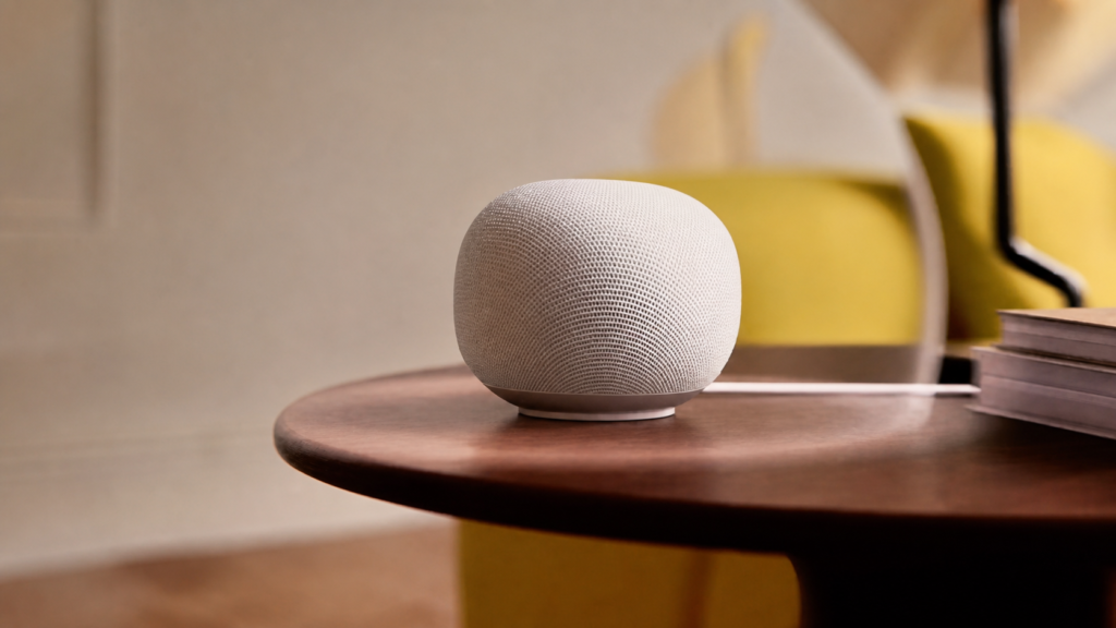 Google Home Speaker with Gemini on a wooden side table in warm indoor light.